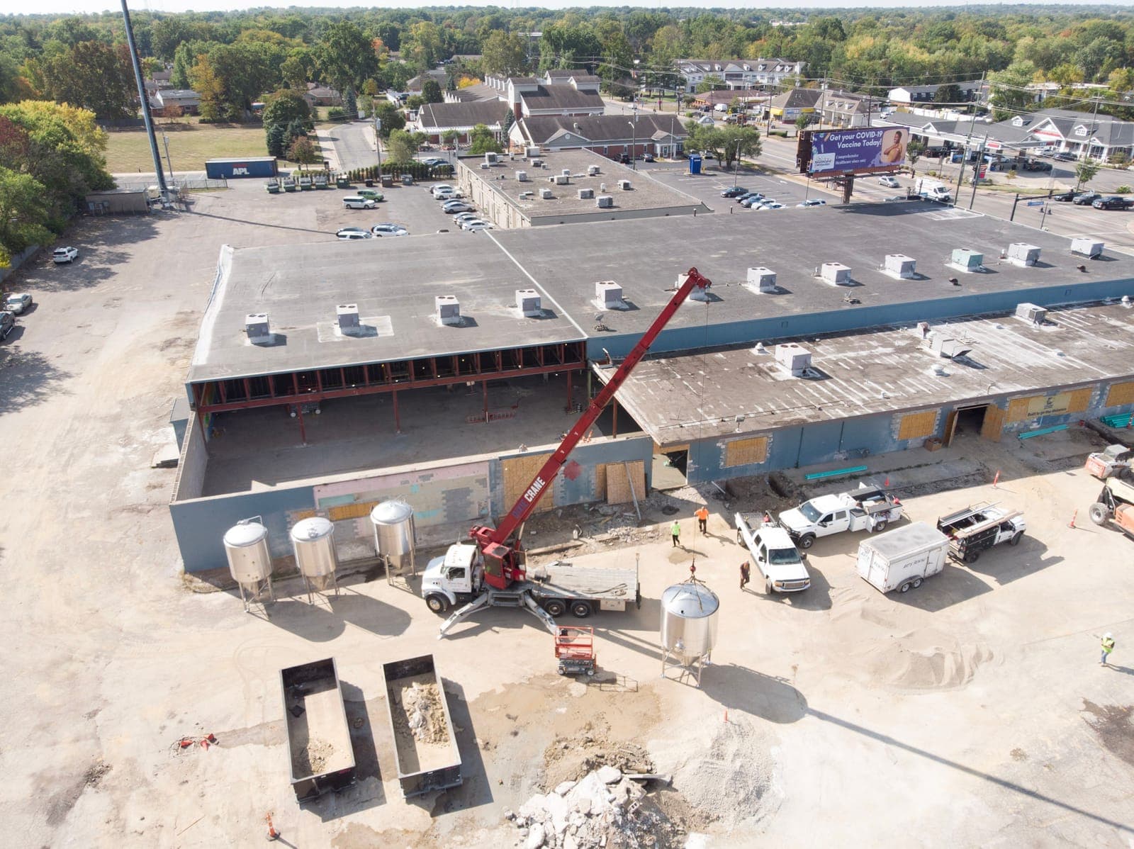 Drone view of the Brentwood building with a crane and brewing tanks waiting beside the new brewery wing