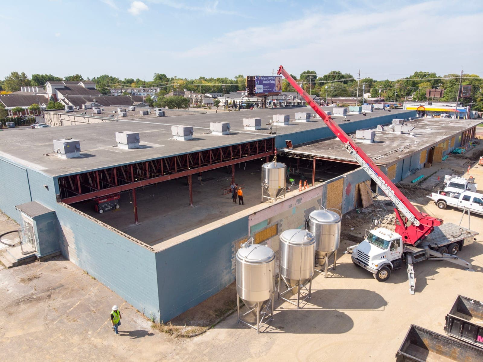 Drone view of a crane lifting equipment beside the building as tanks wait on the ground