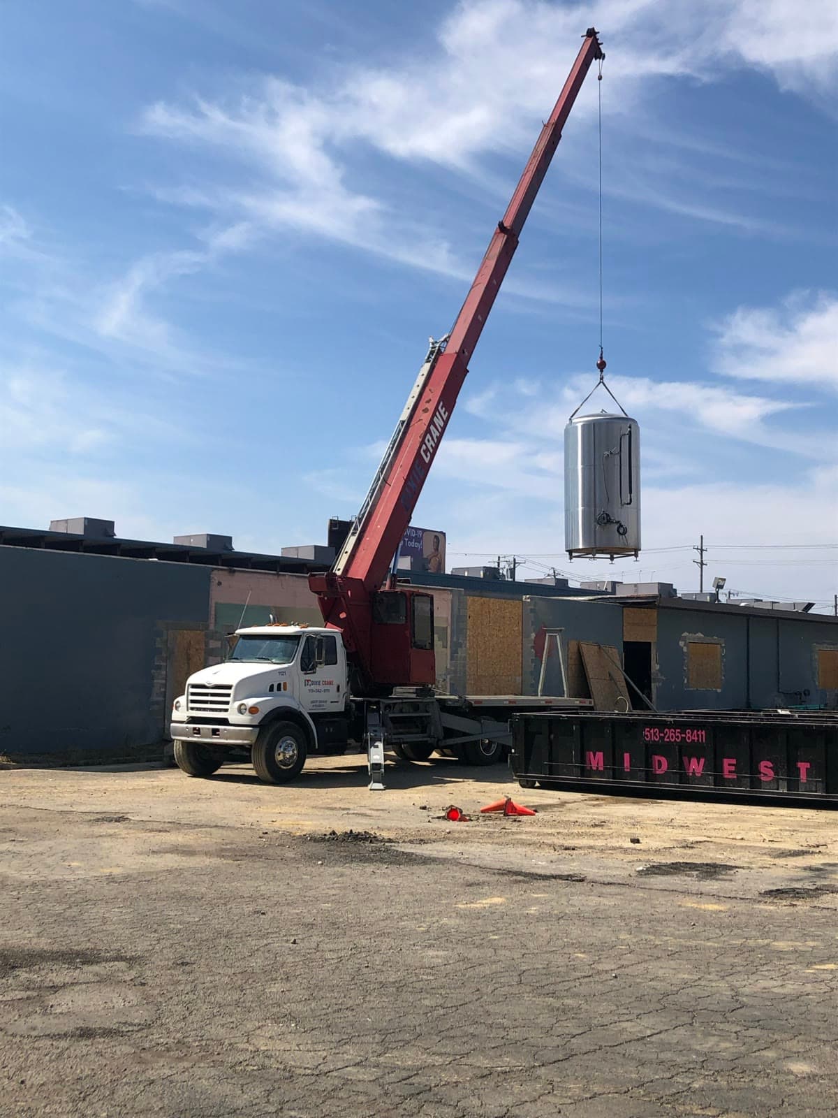 A crane truck lifts a fermentation tank over the old Brentwood Bowl building