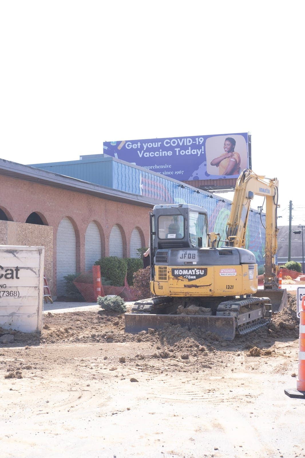 An excavator digging in front of the arched brick entry