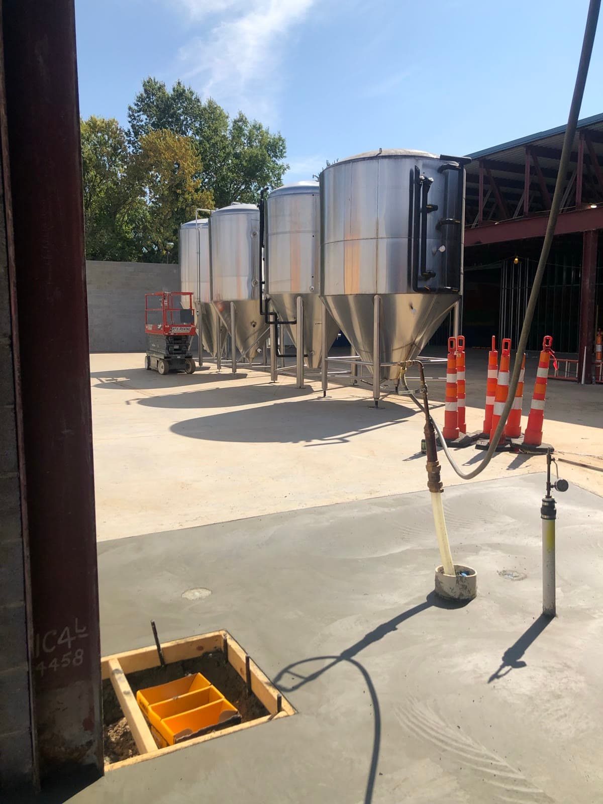 Four fermentation tanks standing on fresh concrete beside the new brewery wing