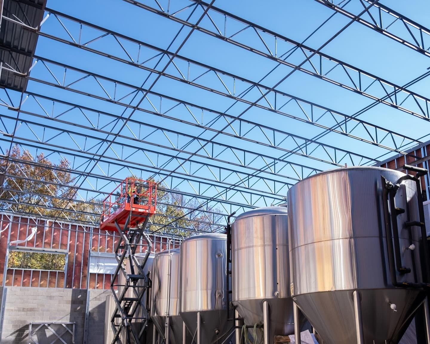 Brewing tanks standing under the new brewery roof framing