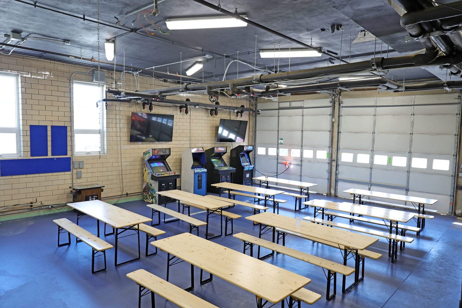 The game room in one of the building's old garage bays, with arcade games and beer-hall tables